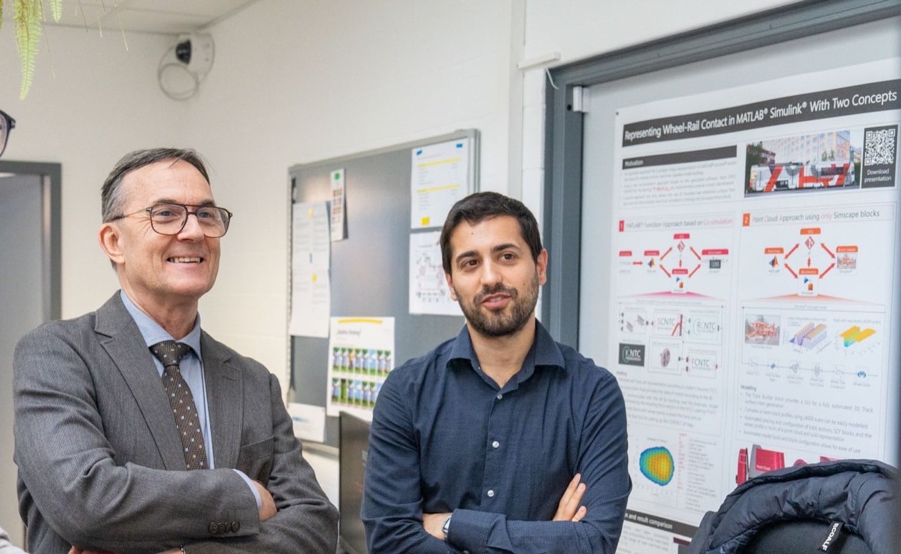 Prof. Oldrich Polach with a Traila engineer in front of a wheel-rail contact poster.