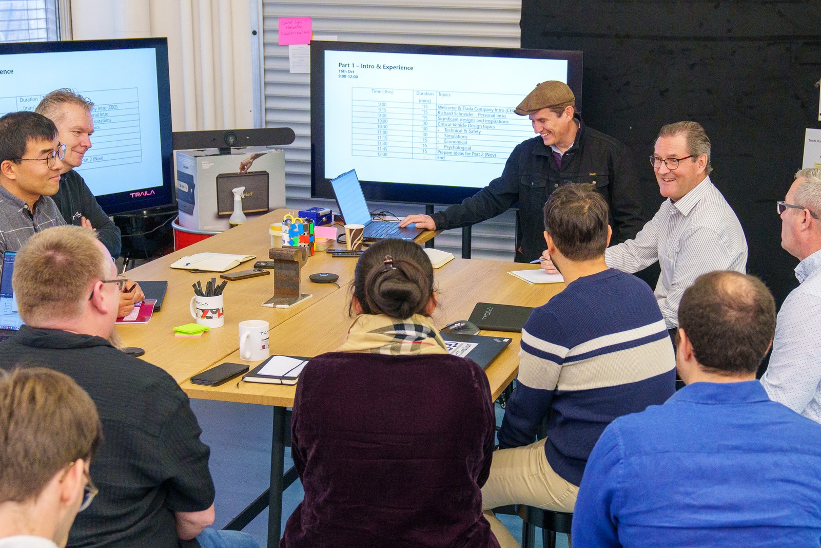 The Traila team around a workshop table, a programme on the screen, guest Richard Schneider standing.