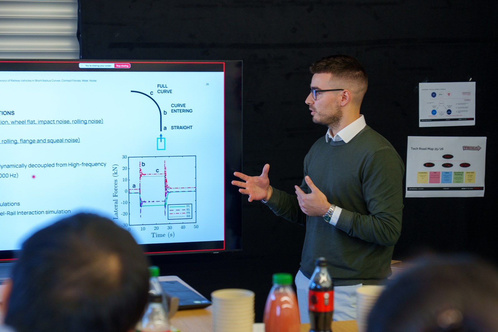Federico Castellini presenting wheel-rail curve dynamics at a Traila tech workshop, colleagues listening in the foreground.