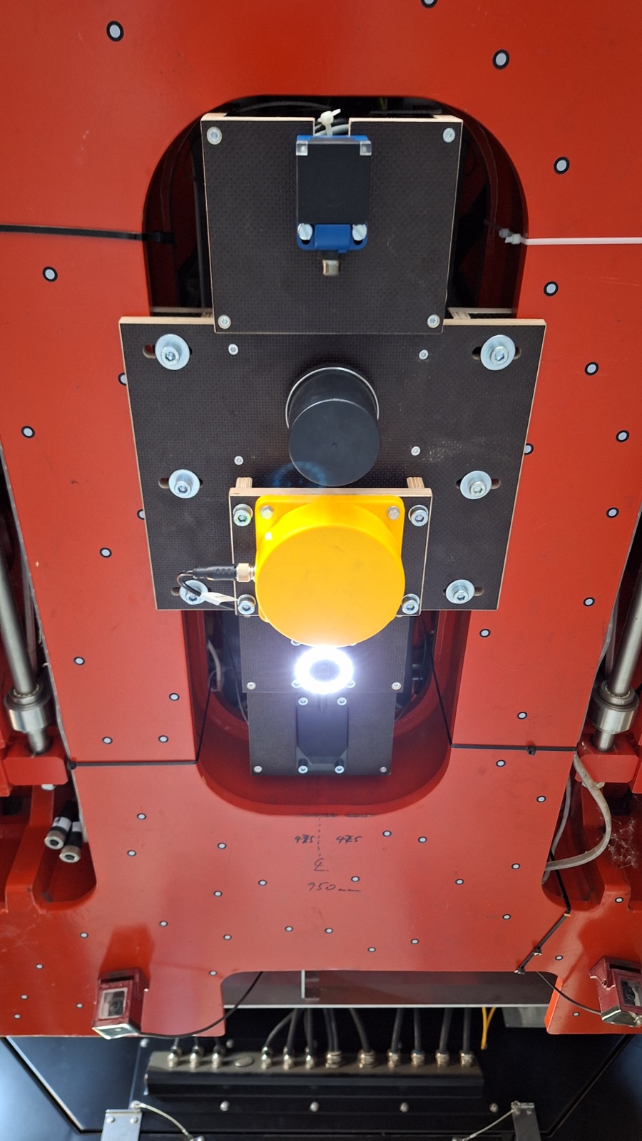A sensor unit mounted beneath the TX4 test vehicle's red bodywork, lens and mounting bracket visible.