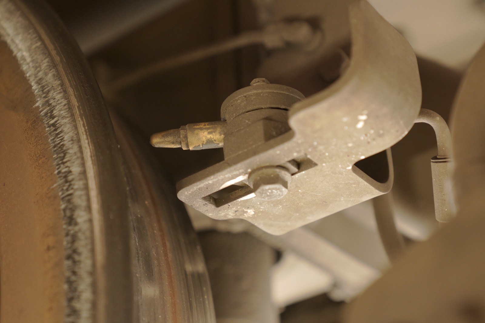 An onboard flange-lubrication nozzle mounted beneath a rail vehicle bogie, close to the wheel.