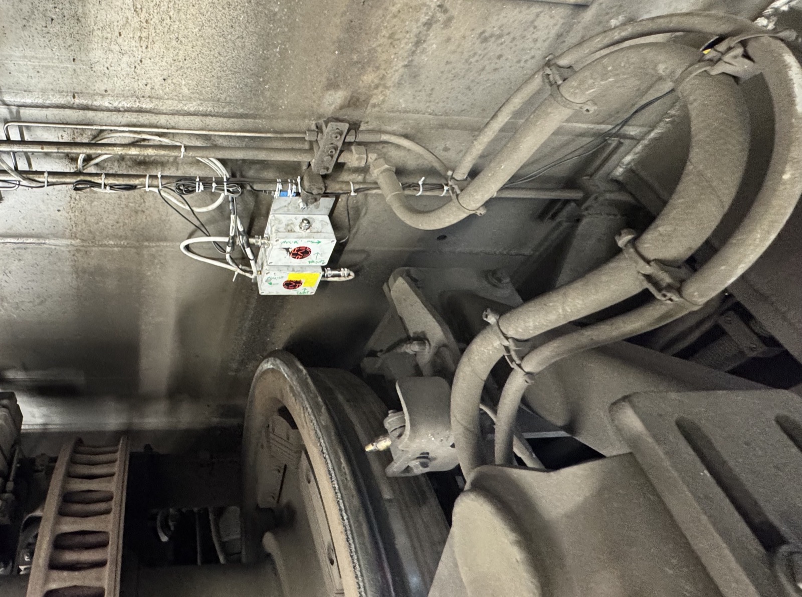 Underside view of a rail vehicle bogie with Traila's hand-built onboard test monitoring unit fitted.